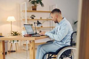 Business worker. Disabled man in wheelchair is at home photo