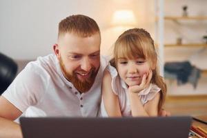 Online learning. Father with his little daughter is at home together photo