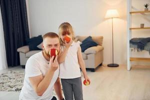 Holding balls. Father with his little daughter is at home together photo