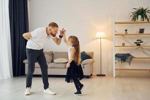 Teaching how to dance. Father with his little daughter is at home together photo