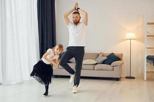 Teaching how to dance. Father with his little daughter is at home together photo