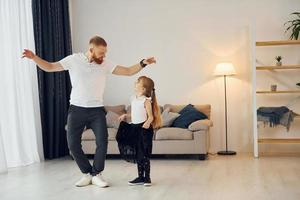 Yoga poses. Father with his little daughter is at home together photo