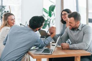 Playing arm wrestling. Group of business people that working on the project in the office photo