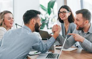 Playing arm wrestling. Group of business people that working on the project in the office photo