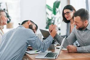 Playing arm wrestling. Group of business people that working on the project in the office photo