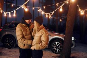 abrazándose unos a otros. pareja de pie en el bosque y celebrando el año nuevo foto