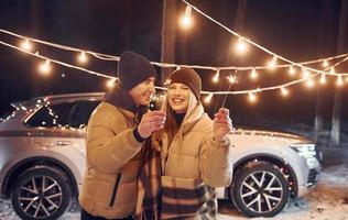 Holiday lights. Couple standing in the forest and celebrating New year photo