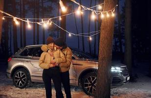 abrazándose unos a otros. pareja de pie en el bosque y celebrando el año nuevo foto