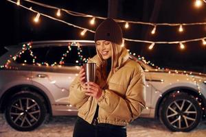 With thermos. Woman standing in the forest and celebrating New year photo