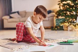 Little boy is in room with christmas tree is on the floor photo