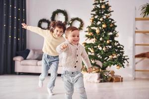 gasto de tiempo activo. el hermano y la hermana pequeños están juntos en la habitación decorada con navidad foto