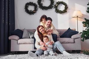 Sitting near sofa. Family celebrating new year with their children at home photo