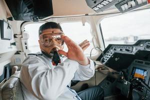 en máscara de oxígeno. piloto en el trabajo en el avión de pasajeros. preparándose para el despegue foto