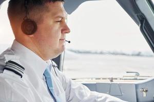 Side view. Pilot in formal wear sits in the cockpit and controls airplane photo