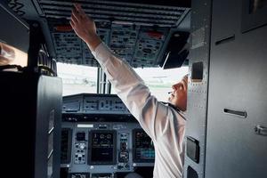 Pilot in formal wear sits in the cockpit and controls airplane photo