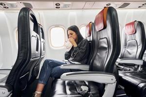 Feel sick. Young woman in casual clothes sits on the passenger seat in the plane photo