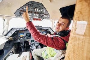 Man in casual clothes sits in the airplane cockpit and looks behind photo