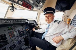 trabajador profesional. el piloto con ropa formal se sienta en la cabina y controla el avión foto