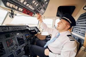 trabajador profesional. el piloto con ropa formal se sienta en la cabina y controla el avión foto