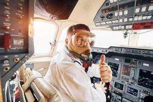 In oxygen mask. Pilot in formal wear sits in the cockpit and controls airplane photo