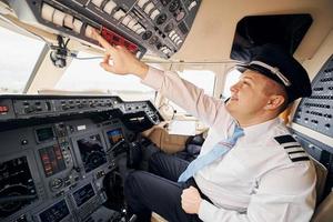 trabajador profesional. el piloto con ropa formal se sienta en la cabina y controla el avión foto