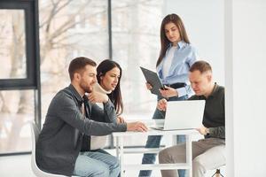 Four people works in the office by sitting by the table indoors photo