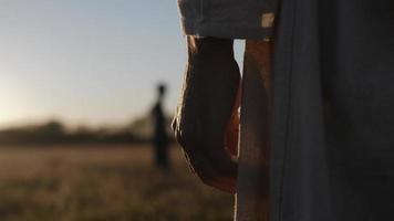 hand- van een gekleed, religieus Mens met ver weg silhouet in een veld- video