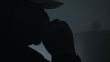 Man Wearing Hat Smoking Cigarette And Blows Smoke In Dark Room video