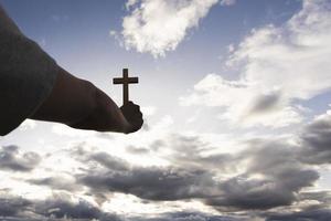 Human hand holding a cross up in the sky. symbol of faith in god Prayer. Deliverance. Prayer. Christian concept. photo