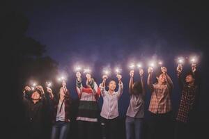 Group of young friends holding and play with fire burning sparklers photo