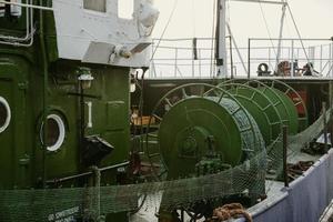 detalle de los carretes de red de pesca verde en la cubierta del barco de pesca de amarre en el puerto de la ciudad polaca de gdansk foto