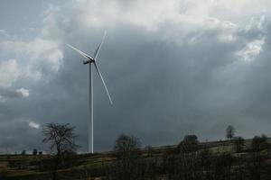 One wind turbine on horizon under the cloudy sky during the spring day on hills of Romania. Copy space photo