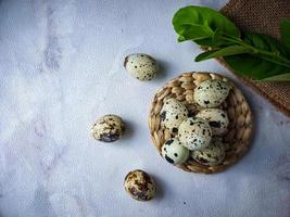 Quail eggs from quail, a collection of quail eggs on a wooden plate against a white wall background photo
