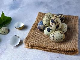 Quail eggs from quail, a collection of quail eggs on a wooden plate against a white wall background photo