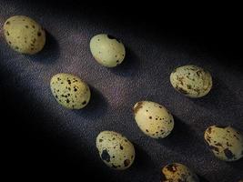 Quail eggs from quail, a collection of quail eggs on a wooden plate with a black sand background photo