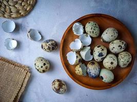 Quail eggs from quail, a collection of quail eggs on a wooden plate against a white wall background photo