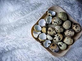Quail eggs from quail, a collection of quail eggs on a wooden plate with a white feather blanket background photo