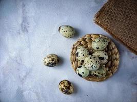 Quail eggs from quail, a collection of quail eggs on a wooden plate against a white wall background photo