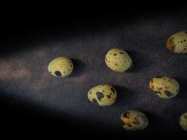 Quail eggs from quail, a collection of quail eggs on a wooden plate with a black sand background photo