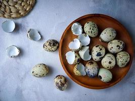 Quail eggs from quail, a collection of quail eggs on a wooden plate against a white wall background photo