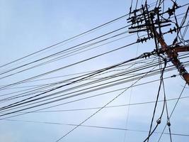 Electrical power junction at the pole reveals the complexity with the bright blue sky clouds photo