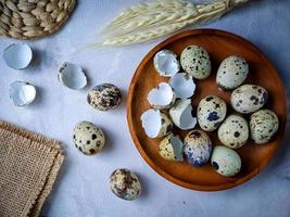 Quail eggs from quail, a collection of quail eggs on a wooden plate against a white wall background photo