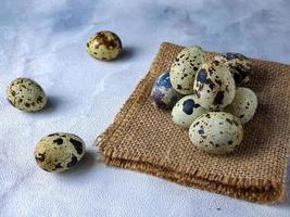 Quail eggs from quail, a collection of quail eggs on a wooden plate against a white wall background photo