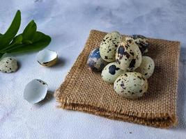 Quail eggs from quail, a collection of quail eggs on a wooden plate against a white wall background photo