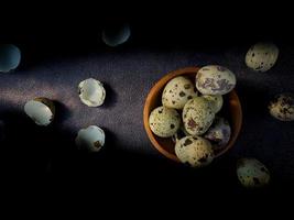 Quail eggs from quail, a collection of quail eggs on a wooden plate with a black sand background photo