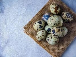 Quail eggs from quail, a collection of quail eggs on a wooden plate against a white wall background photo
