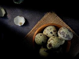 Quail eggs from quail, a collection of quail eggs on a wooden plate with a black sand background photo