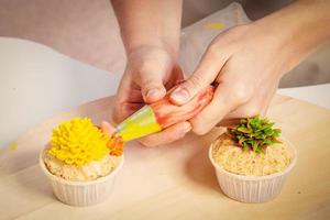 confectioner decorates  cupcake photo