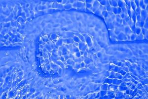 Defocus blurred transparent blue colored clear calm water surface texture with splashes and bubbles. Trendy abstract nature background. Water waves in sunlight with copy space. Blue watercolor shining photo