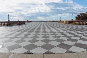 livorno,italia-27 de noviembre de 2022-gente paseando en la terraza mascagni, una espléndida terraza belvedere con superficie pavimentada de tablero de ajedrez, livorno, toscana, italia durante un día soleado. foto